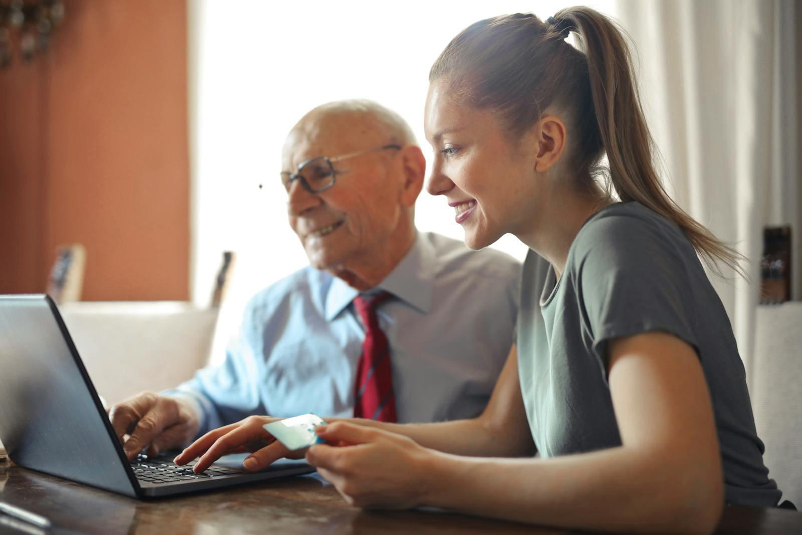 An older man and a younger woman working through something together on a laptop at home