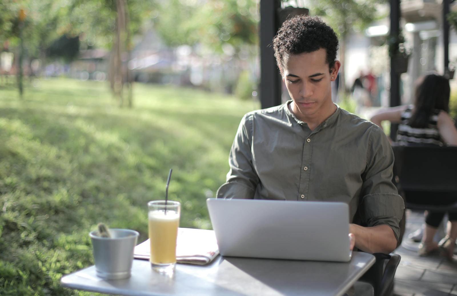 A man working on a laptop at an outdoor cafe table