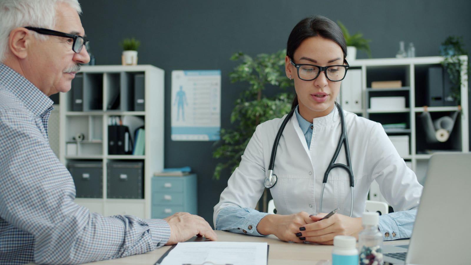 An older man talking through his symptoms with a doctor at her desk